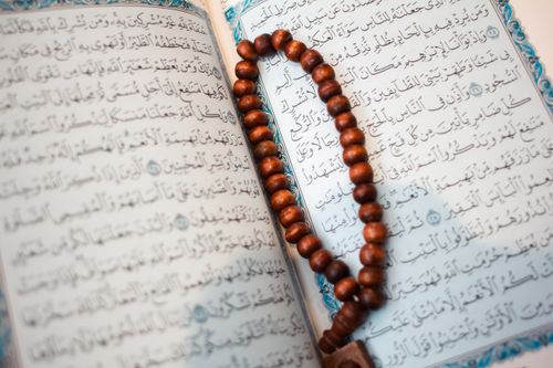Photograph of an open printed Mushaf with tasbih beads for recitation