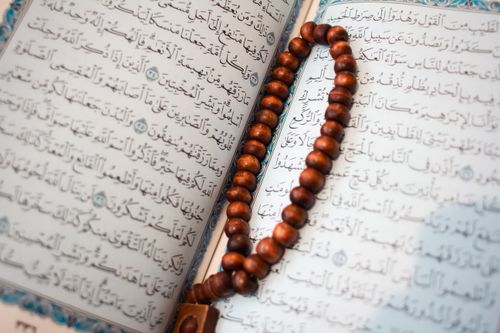 Photograph of an open printed Mushaf with wooden prayer beads
