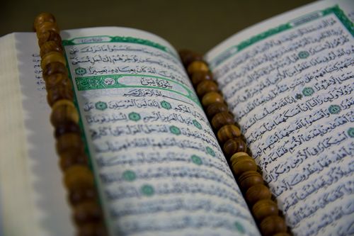 Photograph of a printed Mushaf with wooden tasbih beads on the pages